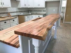 a kitchen with white cabinets and wooden counter tops