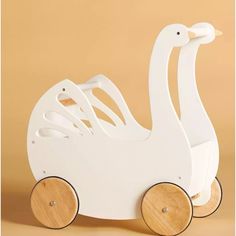 a white swan shaped wooden toy with wheels