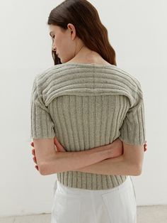 a woman with her arms crossed wearing a sweater