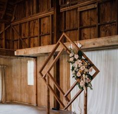 a wedding arch with flowers and greenery on it in front of a wooden wall