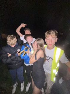 a group of young people standing next to each other in the dark with one pointing at something