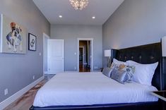 a bedroom with a bed, chandelier and pictures on the wall above it