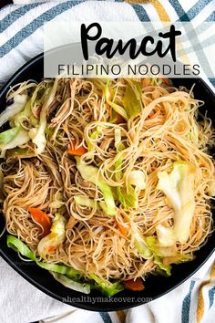 a pan filled with noodles and vegetables on top of a white towel next to a fork