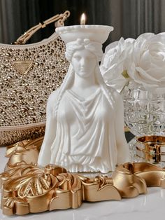 a white statue sitting on top of a table next to some gold bows and flowers