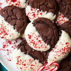 chocolate cookies with white frosting and candy canes on a plate, ready to be eaten