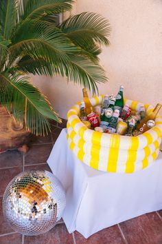 a disco ball sits next to a table with drinks in it and a palm tree