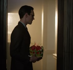 a man in a suit holding a bouquet of flowers and looking at the wall behind him