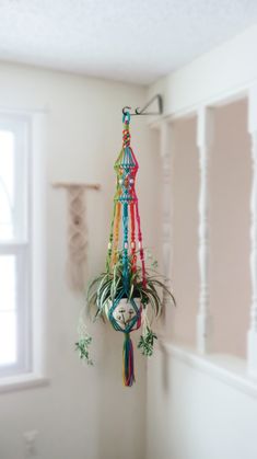 a colorful wind chime hanging from the side of a wall next to a window