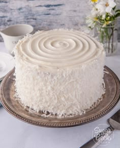 a white cake sitting on top of a silver plate