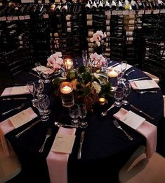 the table is set with place settings and wine bottles in the backgrouds