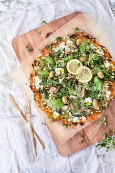 a pizza topped with lots of veggies on top of a wooden cutting board