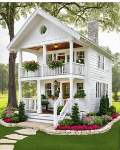 a small white house with flowers in the front and stairs leading up to the second floor