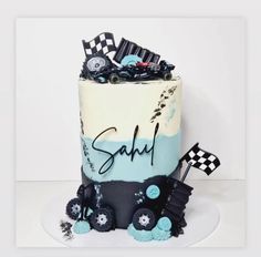 a birthday cake that is decorated with racing cars and race flags on the top tier