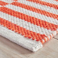 an orange and white crocheted rug is laying on a wooden floor next to a pair of scissors