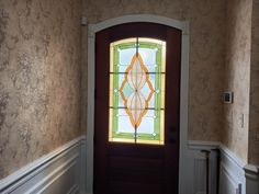 an entryway with a stained glass door and wall papered walls in the background