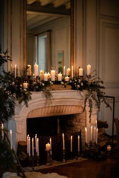 a mantel with candles and greenery on it in front of a fire place