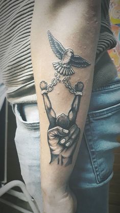 a person with a tattoo on their arm holding a chain and bird above his head