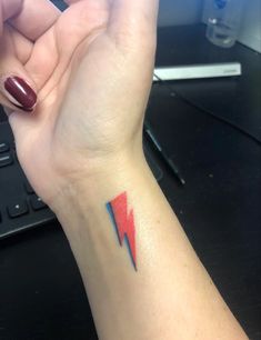 a woman's arm with a red and blue arrow tattoo on it