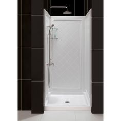 a walk in shower sitting next to a black tiled wall and white tile flooring