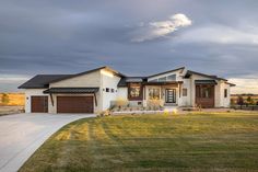 a large home sits in the middle of a grassy area with a cloudy sky above it