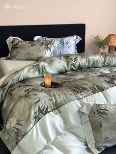 a bed with a black headboard and pillows on top of it, next to a small potted plant