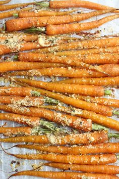 roasted carrots with herbs and seasoning sitting on a sheet of parchment paper, ready to be cooked