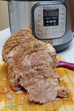 a piece of meat sitting on top of a cutting board next to an instant pot