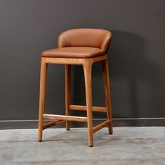 a brown leather bar stool against a gray wall