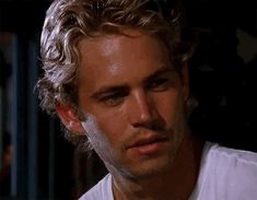 a close up of a person wearing a white shirt and looking at the camera with a serious look on his face