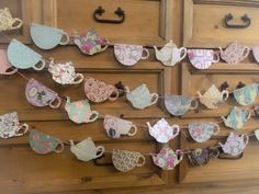 tea cups are hung on a clothes line in front of an old dresser with drawers