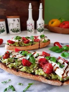 two pieces of bread with tomatoes and avocado on them sitting on a table