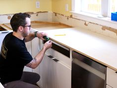 a man in black shirt working on kitchen cabinets