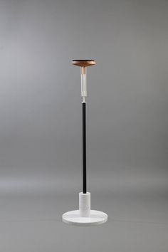 a black and white floor lamp on top of a table next to a gray wall