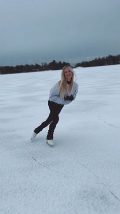 a woman riding skis down a snow covered slope in the middle of a field