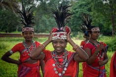 a group of women wearing headdresses standing next to each other in front of trees