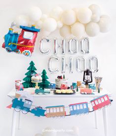 a train themed birthday party with balloons, cake and decorations on a white table top