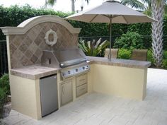 an outdoor kitchen with grill, sink and umbrella