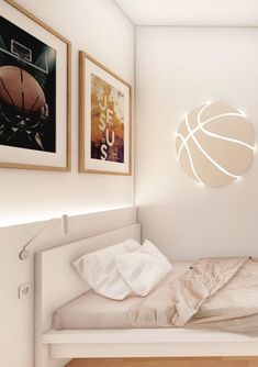 a bed with a basketball on the wall next to two framed pictures and a lamp