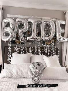 a bed with white sheets and silver balloons on the headboard that say bride to be