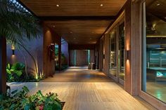 a long hallway with plants and lights on the side walk, leading to an indoor swimming pool