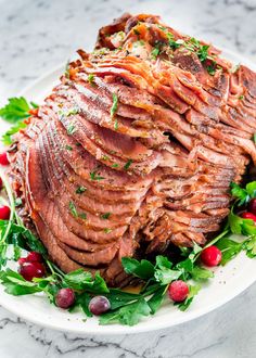 a white plate topped with meat covered in herbs and garnished with cranberries