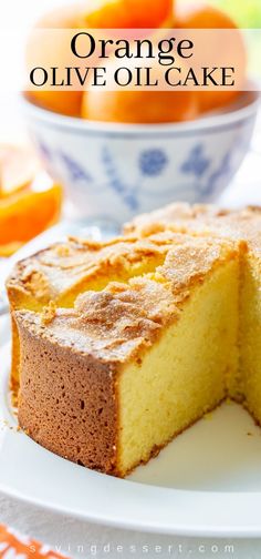 orange olive oil cake on a white plate with a bowl of oranges in the background