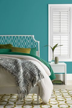 a bedroom painted in teal and white with a bed, nightstands, and window