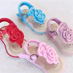 three crocheted sandals with flowers on the bottom and one has a ring at the end