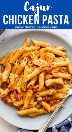 a white plate topped with pasta covered in chicken and tomato sauce next to a fork