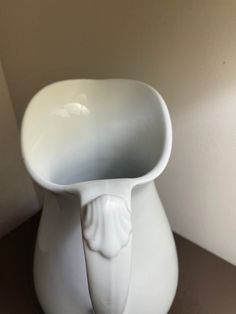 a white vase with an elephant head sticking out of it's side on a table