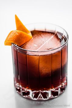 a close up of a drink in a glass with an orange peel on the top