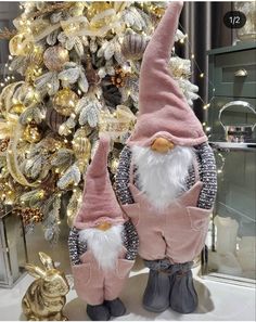 two gnomes are standing in front of a christmas tree