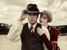 a man and woman standing next to each other in front of an old fashioned car