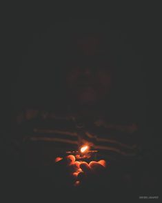 a person holding a lit candle in their hands